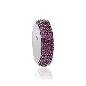 May include: A silver band ring with four rows of pink gemstones. The ring is marked "925" on the inside.