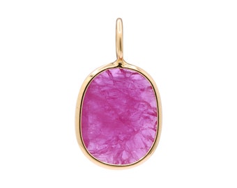Puede incluir: Un colgante de oro con una piedra preciosa ovalada de color rosa con una superficie rugosa y texturizada.
