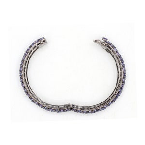 May include: A silver bangle bracelet with a row of small, rectangular, purple gemstones.