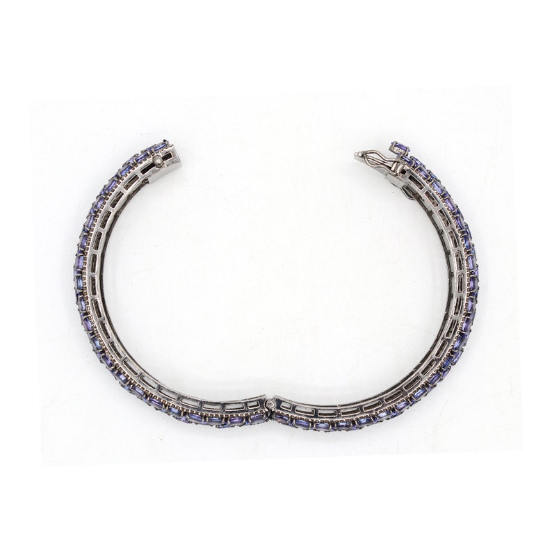May include: A silver bangle bracelet with a row of small, rectangular, purple gemstones.
