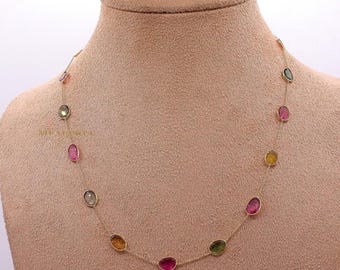 May include: A delicate gold chain necklace featuring a series of small, irregularly shaped, polished gemstones in various colors including pink, yellow, green, and translucent gray, spaced evenly along the thin metallic link chain.