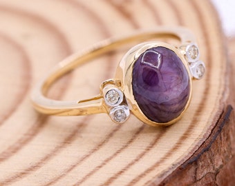 May include: A gold ring featuring a large oval purple gemstone and three smaller round white gemstones.