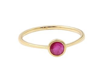 May include: A gold ring with a single, round, red gemstone.