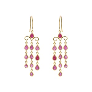 以下が含まれることがあります： ピンク色のしずく型の宝石が付いた、ゴールドカラーのシャンデリアイヤリングのペア。イヤリングは、フックと複数の宝石のストランドが付いた装飾的なトップを備えています。