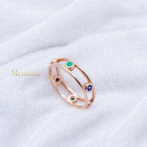 Peut inclure: Une bague en or avec un design à double bande ornée de pierres précieuses vertes et bleues.