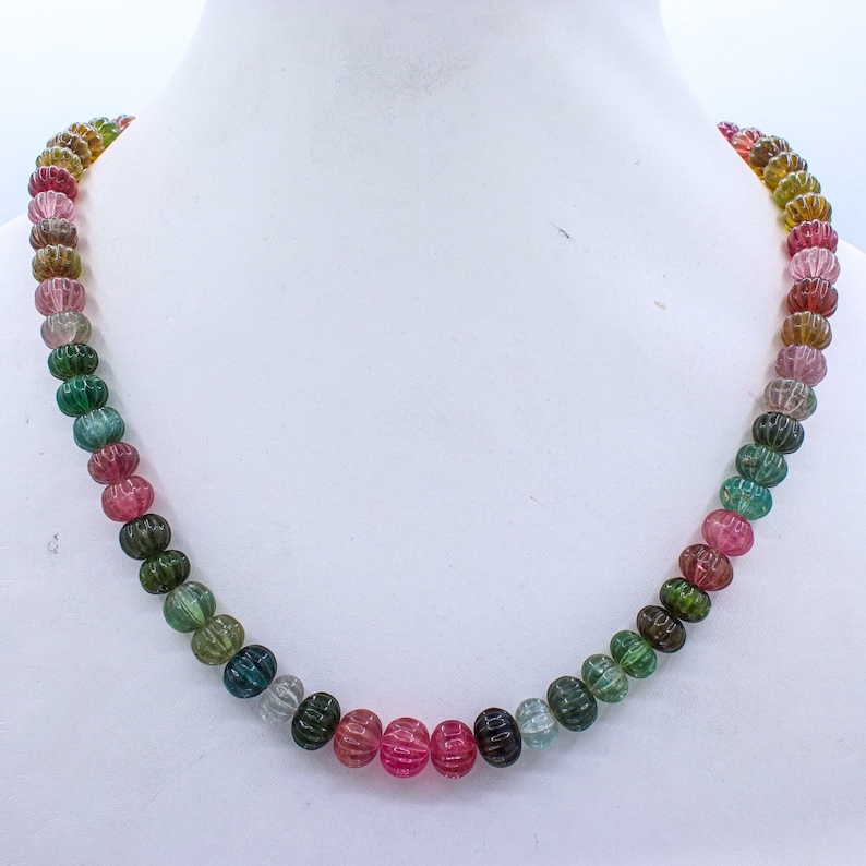 May include: A multi-colored necklace made of round, faceted beads. The beads are a mix of pink, green, and blue.