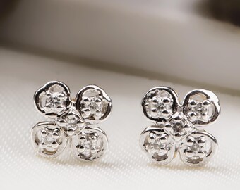 May include: A pair of silver earrings with a four-leaf clover design. Each clover is adorned with small, sparkling diamonds.