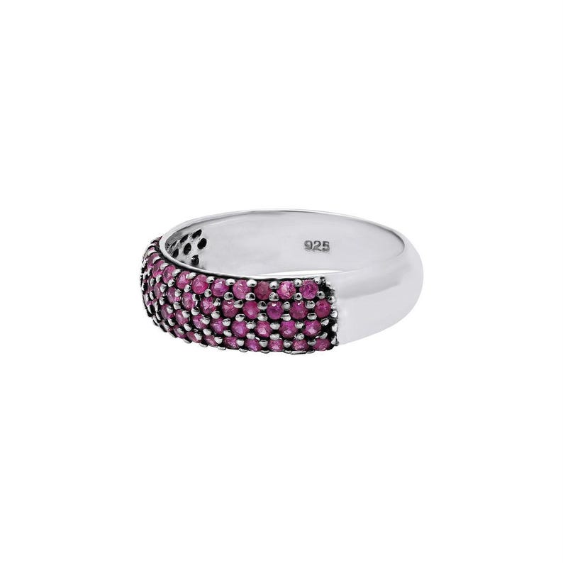 May include: A silver band ring with a row of pink gemstones. The ring is marked "925" on the inside.