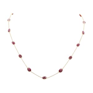 May include: A gold chain necklace with oval-shaped, dark red gemstones.