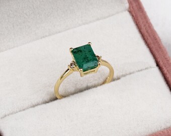May include: A gold ring with a large emerald green gemstone and two smaller diamond accents.