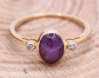 May include: A gold ring featuring a purple oval gemstone with two small diamonds on either side.
