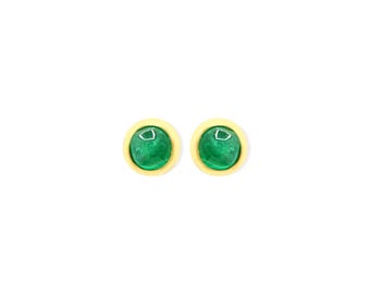 May include: A pair of stud earrings featuring round, vibrant green cabochon stones set within smooth, polished yellow gold-toned circular bezels. The design is simple and symmetrical, highlighting the contrast between the bright green center and the warm gold-colored metal frame.