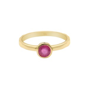 May include: A gold ring with a single, round, bezel-set ruby gemstone.