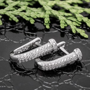 May include: A pair of silver hoop earrings with a pave setting of small clear cubic zirconia stones.