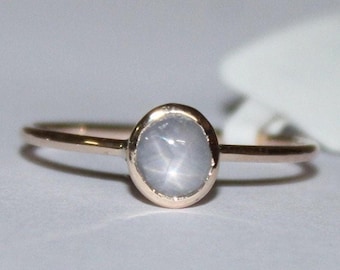 Anillo de zafiro estrella, cabujón gris en oro de 9k, engastado en bisel.
