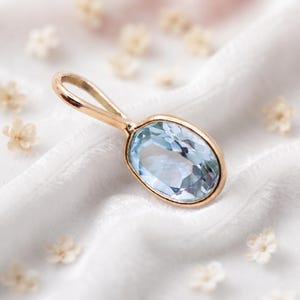 Ciondolo con topazio blu in oro 14 carati, pietra preziosa ovale incastonata a castone.