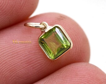 May include: A gold charm featuring a square green peridot gemstone.