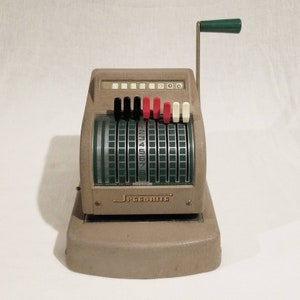 May include: A vintage Speedrite adding machine with a green crank handle, a beige body, and black, red, and white number keys. The machine has a green display with numbers 1 through 9.