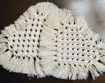 Pode incluir: Dois tapetes de crochê branco com franjas. Os tapetes são feitos com um padrão de nó quadrado.