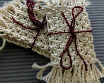 Pode incluir: Dois tapetes de crochê bege com franjas, amarrados com uma fita bordô.