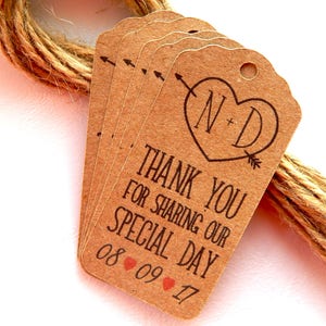 Puede incluir: Etiquetas de agradecimiento de papel kraft marrón con un diseño de corazón y las iniciales N+D. El texto dice "Gracias por compartir nuestro día especial 08 09 17".