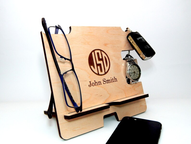Puede incluir: Organizador de madera con ranuras para tel&eacute;fono, reloj, llaves y gafas. El organizador est&aacute; personalizado con las iniciales "JSD" y el nombre "John Smith".