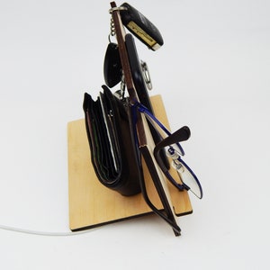 Puede incluir: Un soporte de madera con una cartera negra, unas gafas, un tel&eacute;fono y llaves colgando.