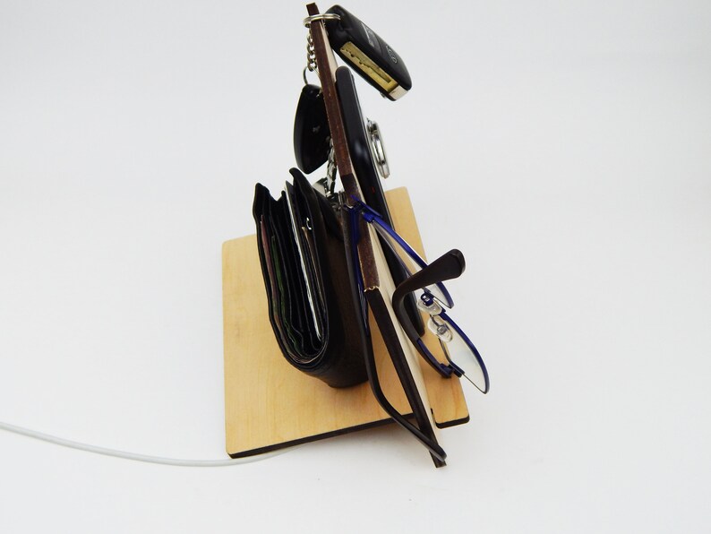Puede incluir: Un soporte de madera con una cartera negra, unas gafas, un tel&eacute;fono y llaves colgando.