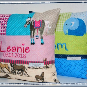 May include: Two personalized pillow covers with embroidered designs. One pillow features a horse with a pink saddle and the name Leonie with the date 07.01.2018. The other pillow features a blue elephant and the name Tom.