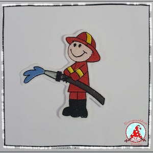 Könnte beinhalten: Ein gestickter Aufnäher mit einem Cartoon-Feuerwehrmann in roter Uniform mit gelben Streifen, rotem Helm und schwarzen Stiefeln. Die Figur hält einen schwarzen Schlauch, aus dem ein blauer Wasserstrahl kommt. Das Motiv hat einen weißen Rand.