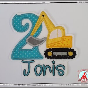 Könnte beinhalten: Ein blauer und gelber gestickter Aufnäher mit der Zahl 2 und einem gelben Bagger. Der Name "Jonis" ist unter dem Bagger gestickt.