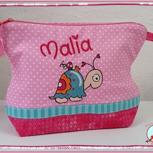 May include: Pink polka-dot cosmetic bag with the name "Malia" embroidered in red. Features a cartoon snail with a blue shell and orange accents. The bag has a turquoise stripe and a pink zipper.