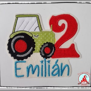 Könnte beinhalten: Grüner Traktor mit einer roten Zahl 2 und dem Namen Emilian in blauen Buchstaben auf weißem Hintergrund.