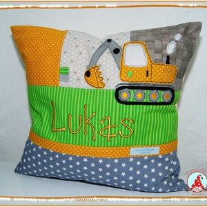Könnte beinhalten: Ein grünes und gelbes Patchwork-Kissen mit einem gelben Bagger-Design und dem Namen "Lukas" bestickt.