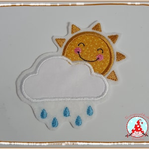 Könnte beinhalten: Ein Stoffaufnäher mit einer lächelnden gelben Sonne mit orangefarbenen Strahlen und rosa Wangen, die teilweise hinter einer weißen Wolke mit fünf gestickten blauen Regentropfen hervorschaut. Der Text Zwergennähkiste Franziline ist unten rechts zu sehen.