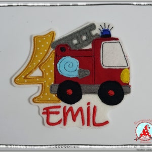 Könnte beinhalten: Ein Stoffaufnäher mit einer gelben Zahl vier mit weißen Punkten, einem roten Feuerwehrauto mit grauer Leiter, blauem Blaulicht und hellblauem Schlauch. Der Name EMIL ist in roter Schrift unter dem Fahrzeug auf weißem Filz gestickt.