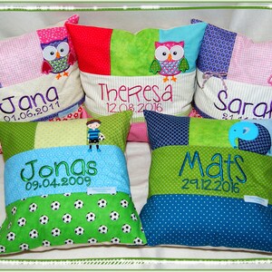 Könnte beinhalten: Fünf bunte Patchwork-Kissen mit gestickten Namen und Geburtsdaten. Jedes Kissen zeigt eine andere Tier-Applikation: eine Eule, einen Fußball, einen Elefanten und zwei weitere Eulen.