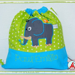 Könnte beinhalten: Eine grüne Kordeltasche mit weißen Punkten und einem grauen Elefanten mit einem blauen Rüssel. Die Tasche hat einen blauen Boden mit dem Namen "Paul Emilio" in grün gestickt.