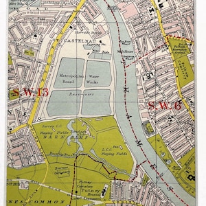 Op de afbeelding: Een ingelijste vintage kaartprint met een gedetailleerde cartografische weergave van een stedelijk gebied. De kaart toont straten, waterpartijen en groene ruimtes, met tekstlabels en rasterlijnen. Het kleurenpalet omvat tinten groen, roze en geel.