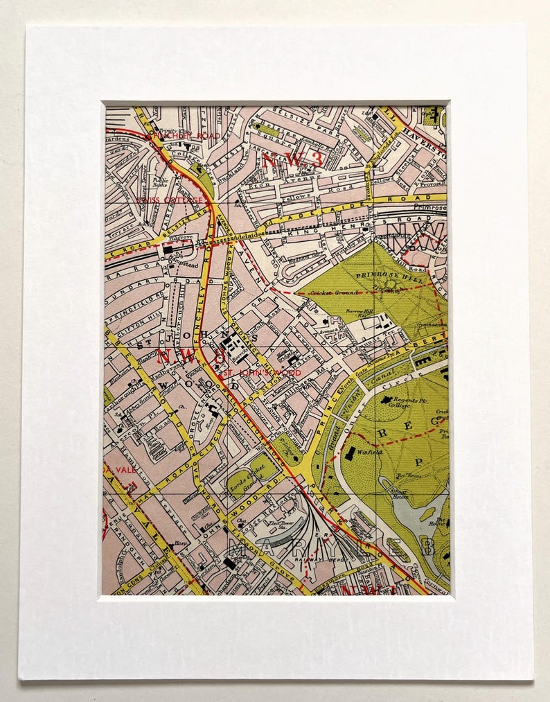 Pu&ograve; includere: Stampa di mappa vintage incorniciata con una mappa stradale dettagliata con strade, parchi ed edifici. La mappa ha una tavolozza di colori rosa, giallo e verde, con il rosso che evidenzia i percorsi chiave. La stampa &egrave; incorniciata in un passe-partout e una cornice bianchi.