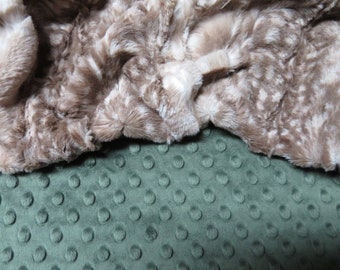 May include: A brown faux fur fabric with a white pattern, folded over a green minky fabric with a dotted texture.