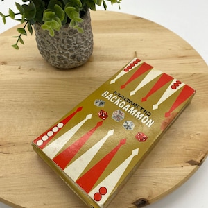 May include: A vintage game box for Magnetic Backgammon. The box is gold with red and white accents. It features a game board design and dice.