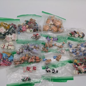 Könnte beinhalten: Eine Sammlung kleiner, mehrfarbiger Miniaturfiguren, verpackt in mehreren durchsichtigen, wiederverschließbaren Plastikbeuteln. Das Sortiment umfasst verschiedene Formen und bemalte Details mit diversen Figuren und Objekten.