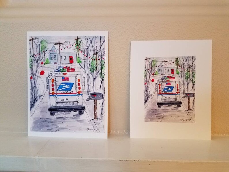 Op de afbeelding: Een aquarel van een witte USPS-postwagen die over een straat rijdt die versierd is met rode kerstverlichting. De wagen vervoert pakketten en rijdt langs een huis met een rode deur.