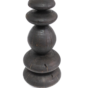 May include: A dark brown wooden sculpture composed of stacked, rounded shapes. The sculpture has a textured surface with visible wood grain and knots. The design features a series of varying sized, disc-like forms, creating a unique, abstract aesthetic.
