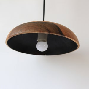 May include: A wooden pendant light with a black interior and a single light bulb.