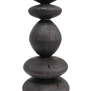 May include: A dark stained wooden sculpture composed of stacked, rounded shapes. The sculpture has a natural wood grain texture and a smooth, polished finish. The design is abstract and modern, suitable for home decor.