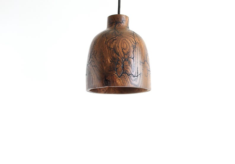 Peut inclure: Une suspension en forme de cloche fabriqu&eacute;e en bois brun avec un grain naturel apparent. La surface ext&eacute;rieure pr&eacute;sente des marques de br&ucirc;lure fractales sombres et ramifi&eacute;es qui cr&eacute;ent un motif semblable &agrave; de la foudre sur le corps en bois.