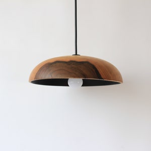 May include: A wooden pendant light with a dark wood grain and a black cord. The light is hanging from a white ceiling.