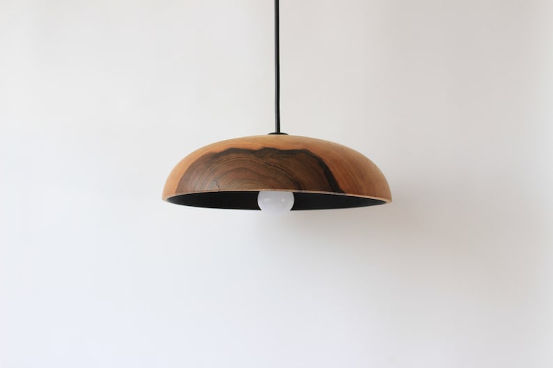 May include: A wooden pendant light with a dark wood grain and a black cord. The light is hanging from a white ceiling.